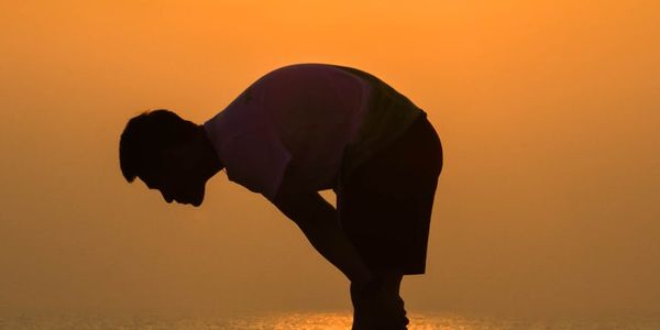Silhouette of a person stretching at sunrise.
